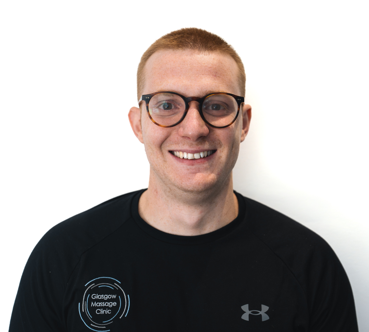 Glasgow Massage Clinic team member smiling at the camera, wearing glasses and a branded black clinic top.