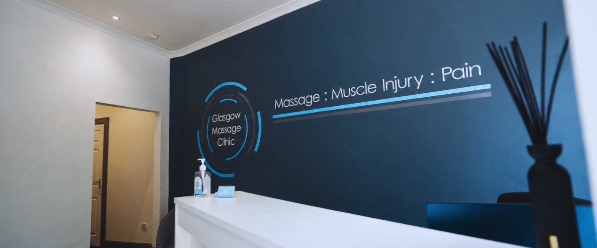 Glasgow Massage Clinic reception area with branded wall signage, white front desk and treatment information on display.